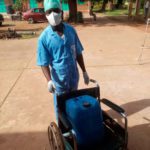 Opérateur dans un centre de santé qui transporte un bidon de désinfectant sur une chaise roulante au Burkina Faso